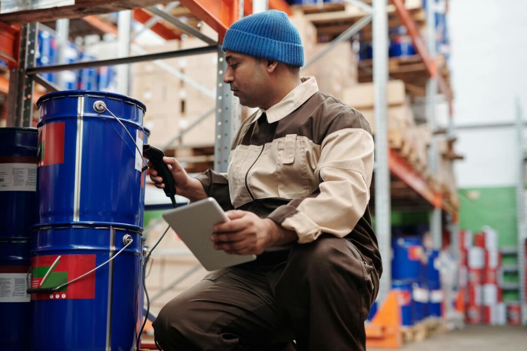 Warehouse employee scanning inventory using tablet and scanner in industrial storage area.